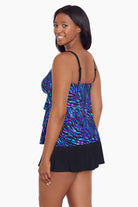 Woman turned left wearing a black and blue safari printed ruffled skirtini swimsuit