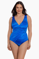 Woman wearing a blue streaked pattern one-piece swimsuit with O ring on side 