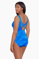 Woman turned left wearing a blue streaked pattern one-piece swimsuit with X back