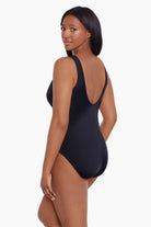 Woman faced left wearing a black mesh high neck one-piece swimsuit
