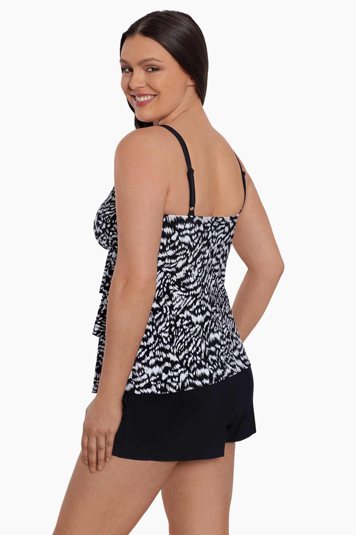 Woman faced left wearing a black and white abstract printed ruffled skirtini swimsuit