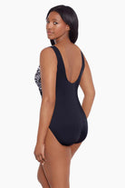 Woman turned left wearing a black and white abstract printed one-piece swimsuit with mesh cutout on the side