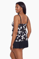 Woman turned left wearing a black and white floral ruffled skirtini swimsuit