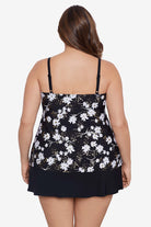 Woman faced away wearing a small white flower printed black skirtini swimsuit with ruffles