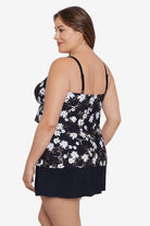 Woman turned left wearing a small white flower printed black skirtini swimsuit with ruffles