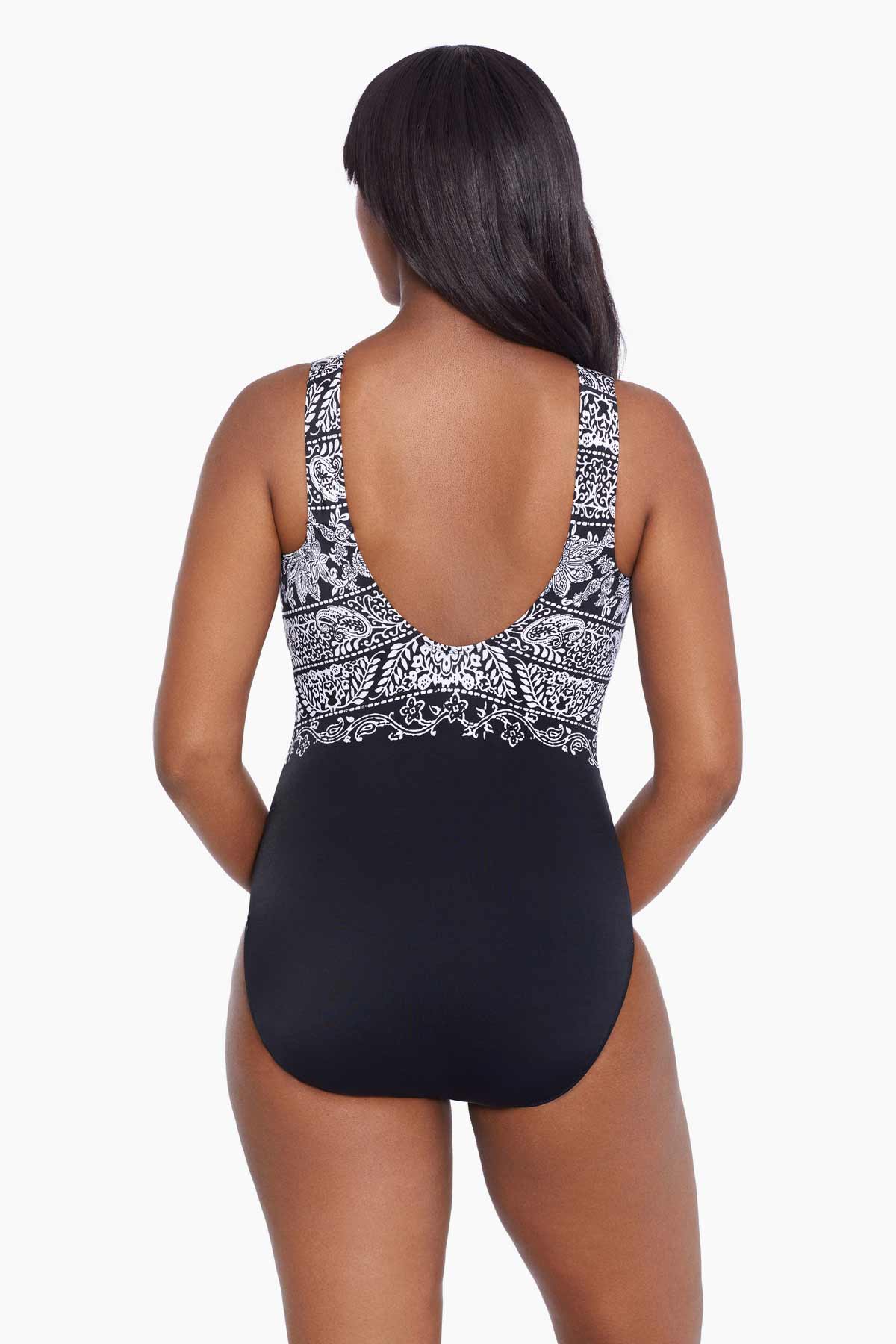 Woman faced away wearing a black and white garland printed one-piece swimsuit