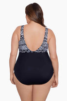Woman faced away wearing a black and white garland printed one-piece swimsuit