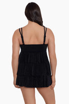 Woman faced away wearing a black faint animal printed tiered swim dress