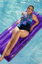 Woman on pool float wearing a half zebra print with blue and pink florals down the middle one-piece swimsuit