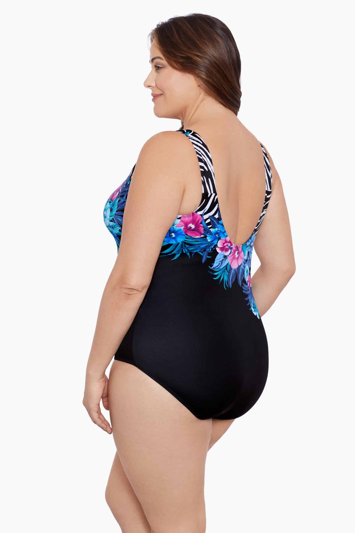 Woman turned left wearing a half zebra print separated by a floral print one-piece swimsuit