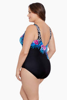 Woman turned left wearing a half zebra print separated by a floral print one-piece swimsuit