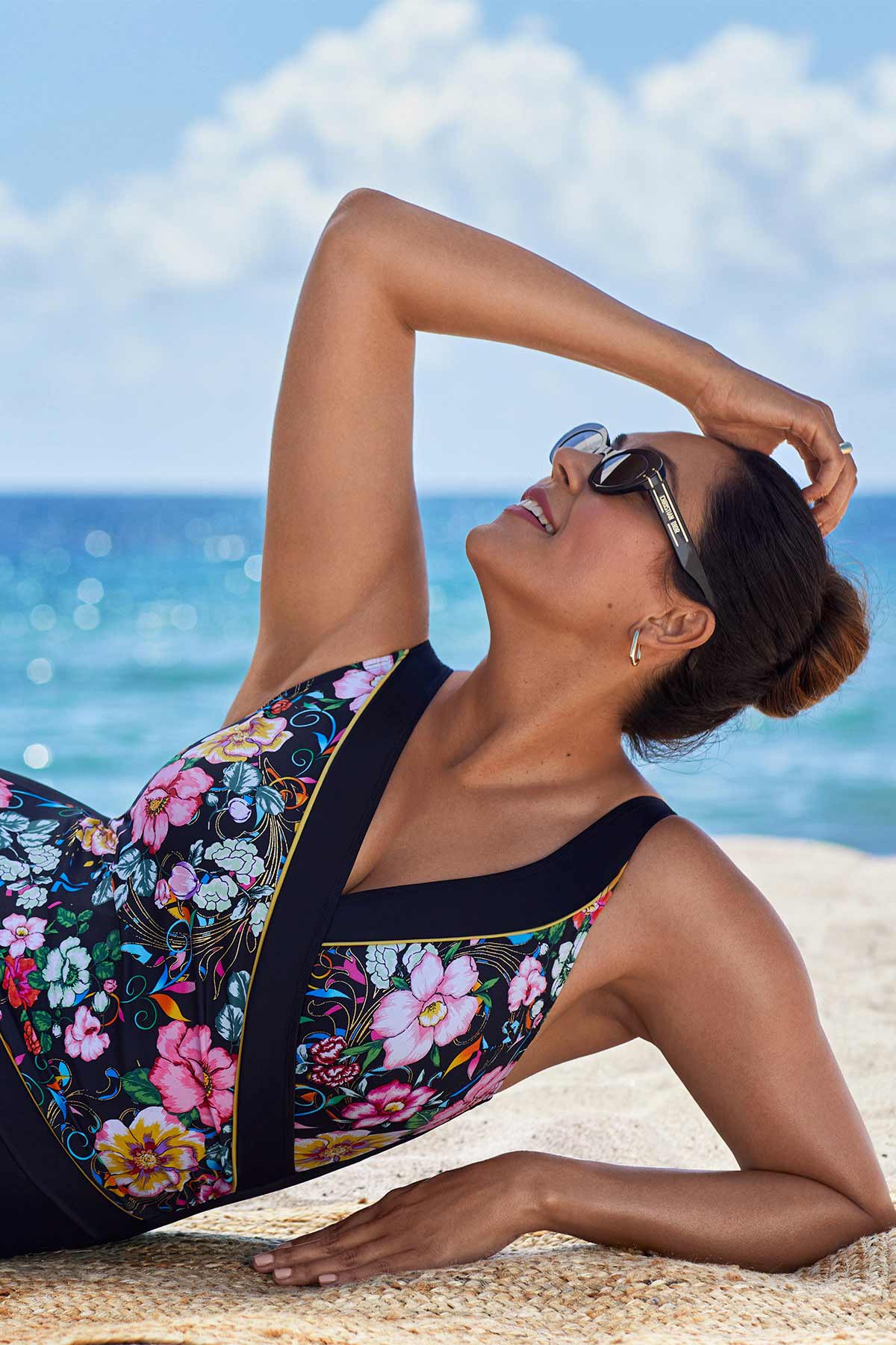 Woman on beach wearing a floral printed one-piece swimsuit