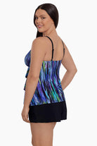 Woman faced left wearing a multicolored streak printed ruffled swim shortini