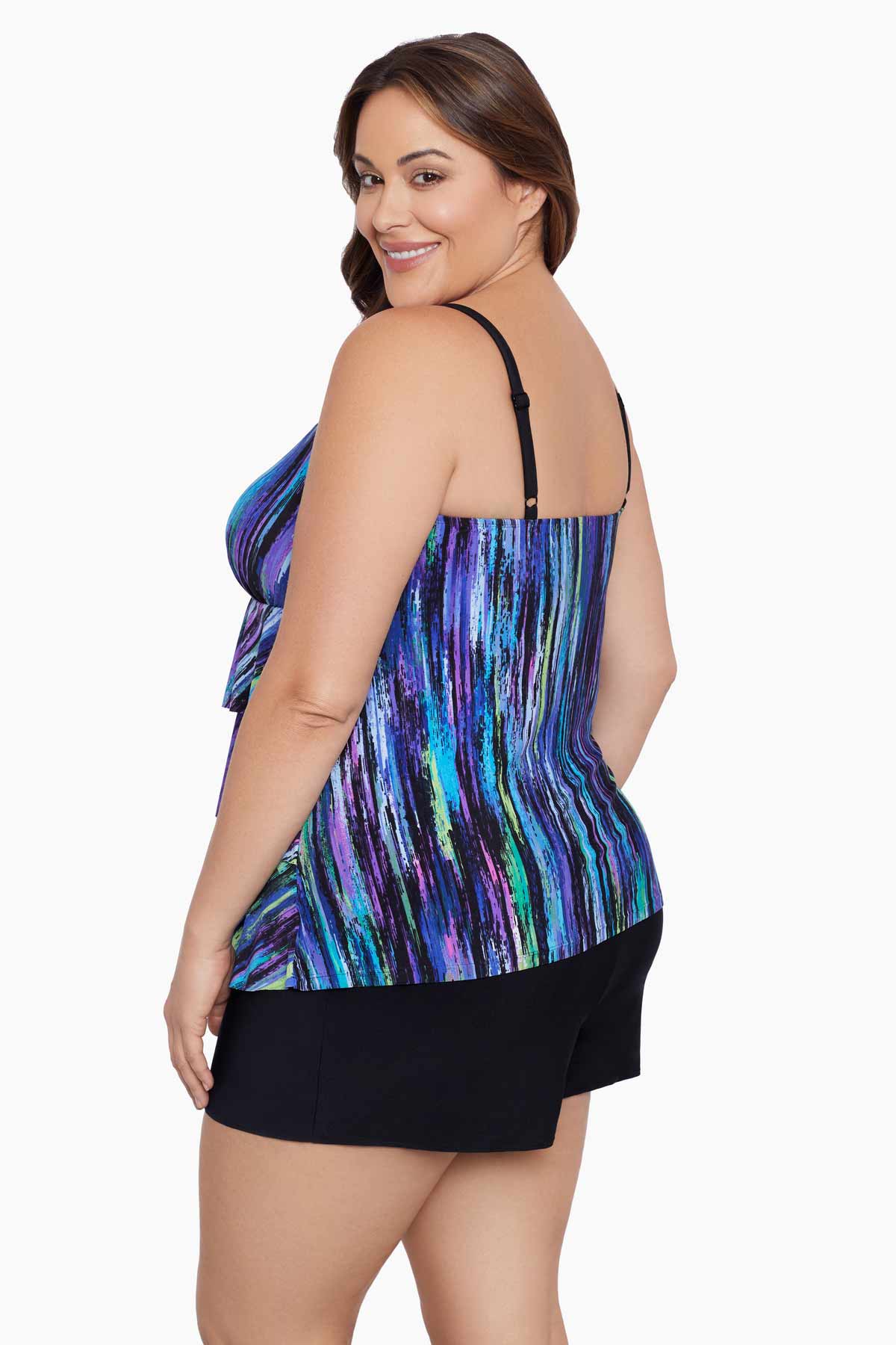 Woman faced left wearing a blue and green streak printed ruffle shortini swimsuit