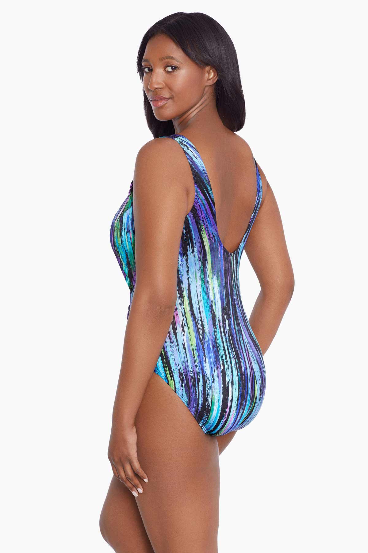 Woman faced left wearing a multicolored streak printed one-piece swimsuit with a side twist
