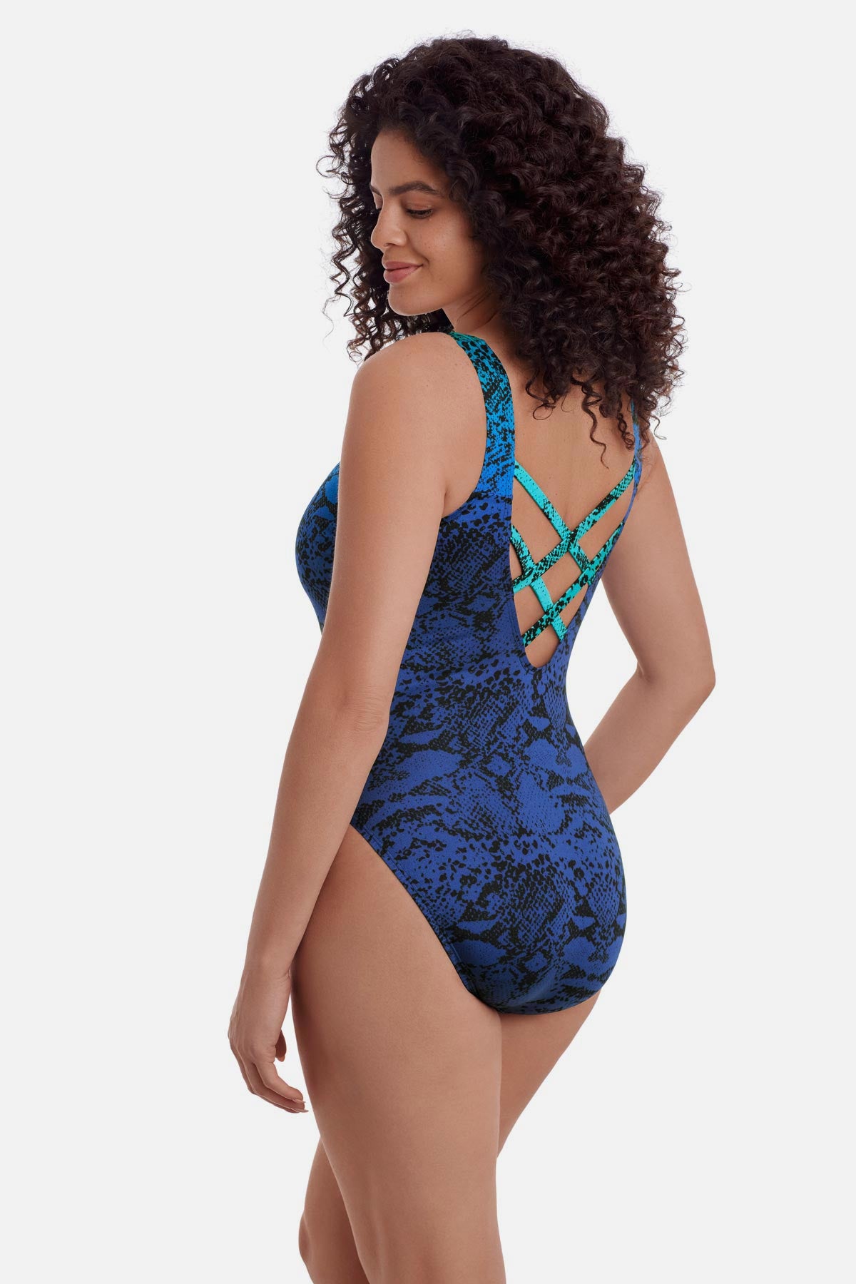 Woman turned left wearing an animal-esque print one-piece swimsuit in blue with an X back