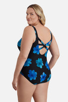 Woman turned left wearing a large blue flower printed one-piece swimsuit
