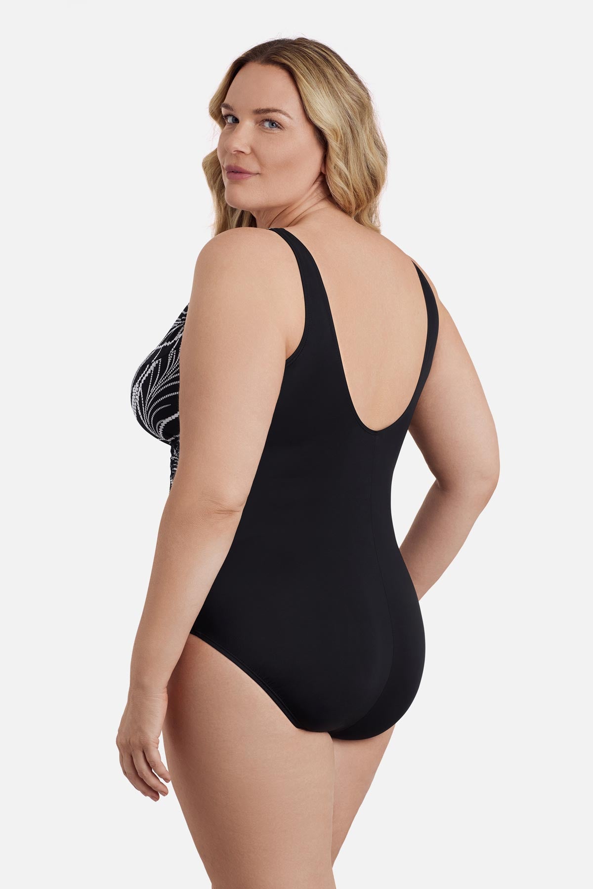Woman turned left wearing a black and white dotted leaf pattern one-piece swimsuit