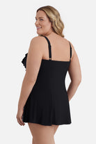 Woman faced left wearing a black swim dress with a ruffled neckline