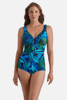 Woman wearing a blue and green one-piece swimsuit with ruffles down the front