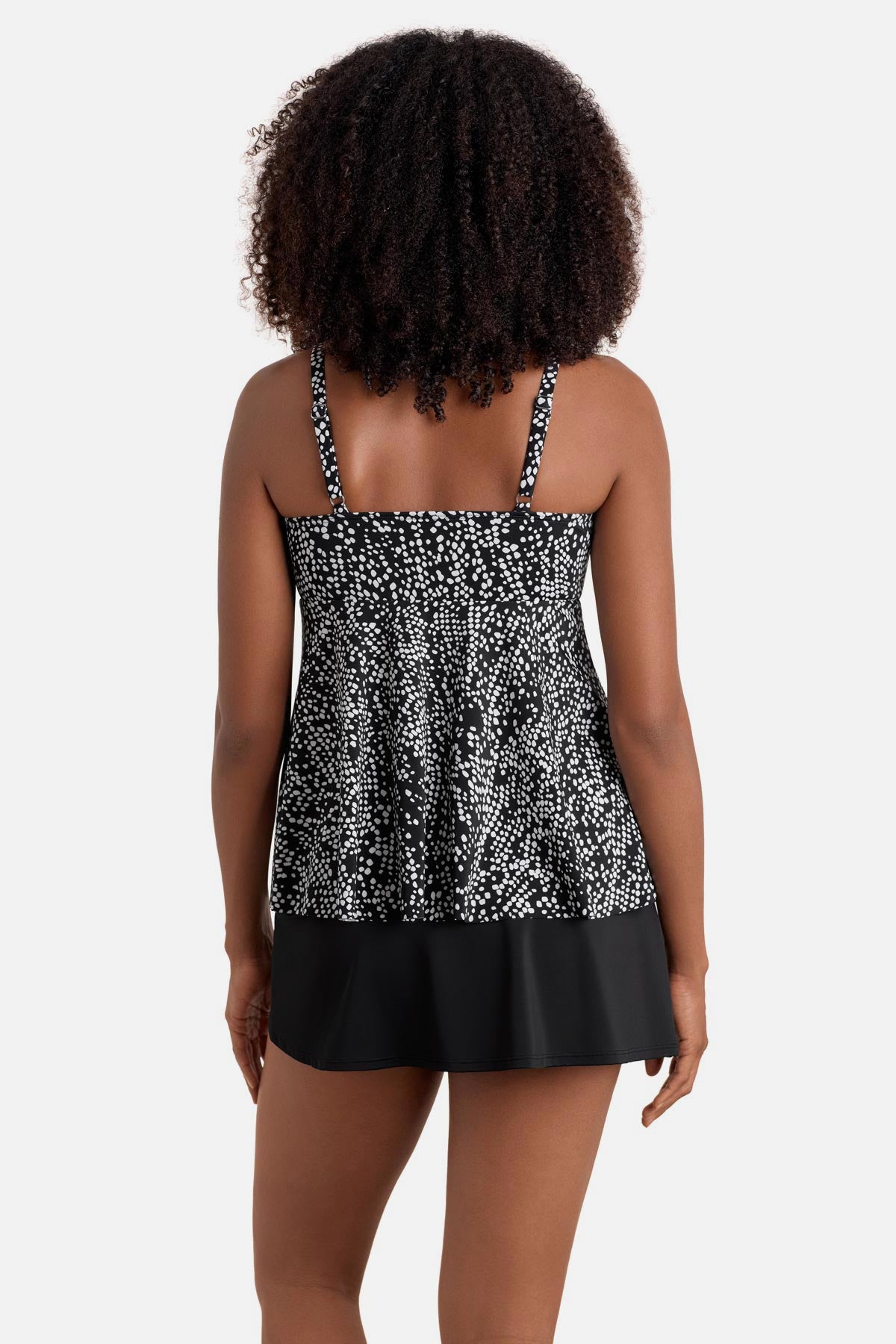 Woman turned away wearing a black and white dotted print tankini top