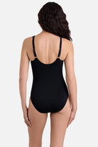 Woman turned away wearing a black one-piece swimsuit with ruffles on the neckline