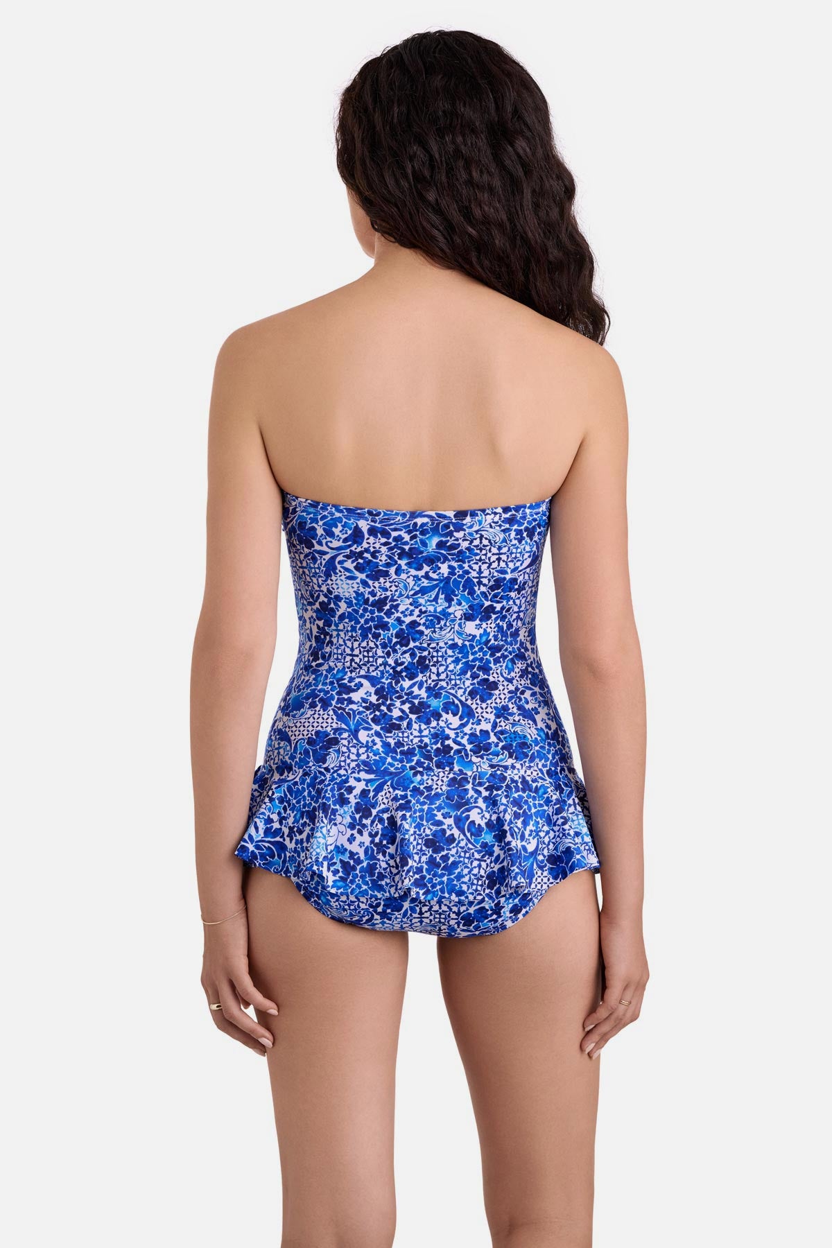 Woman turned away wearing a blue and white floral printed skirted one-piece swimsuit