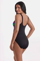Woman turned left wearing a rainbow tie dye-esque one-piece swimsuit
