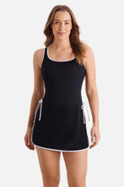 Woman wearing a black swim dress with white piping/edges
