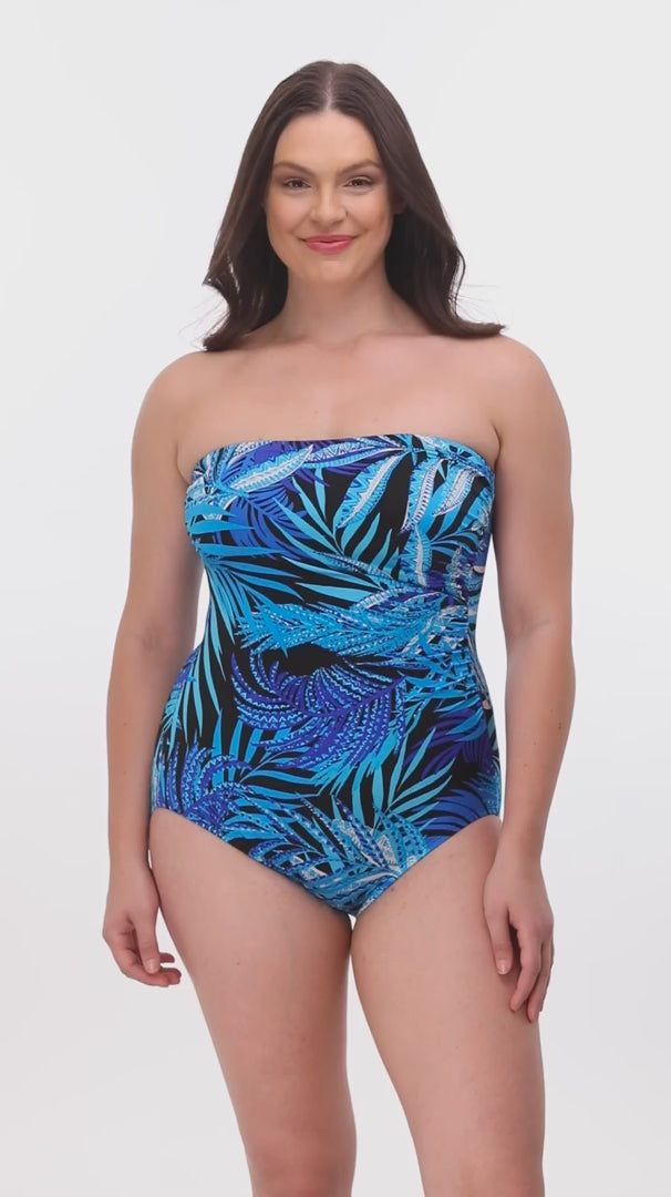 Woman wearing a blue palm leaf printed bandeau one-piece swimsuit