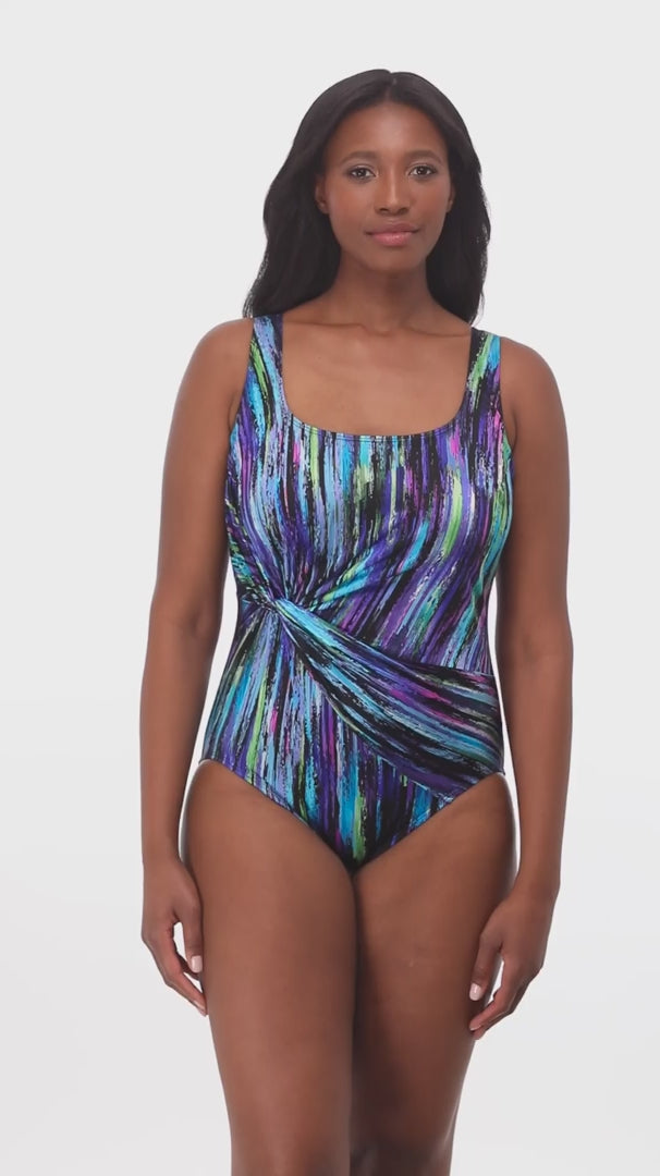Woman wearing a multicolored streak printed one-piece swimsuit with a side twist