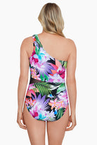 Woman turned away wearing a tropical printed one shoulder one-piece swimsuit with mesh cutout