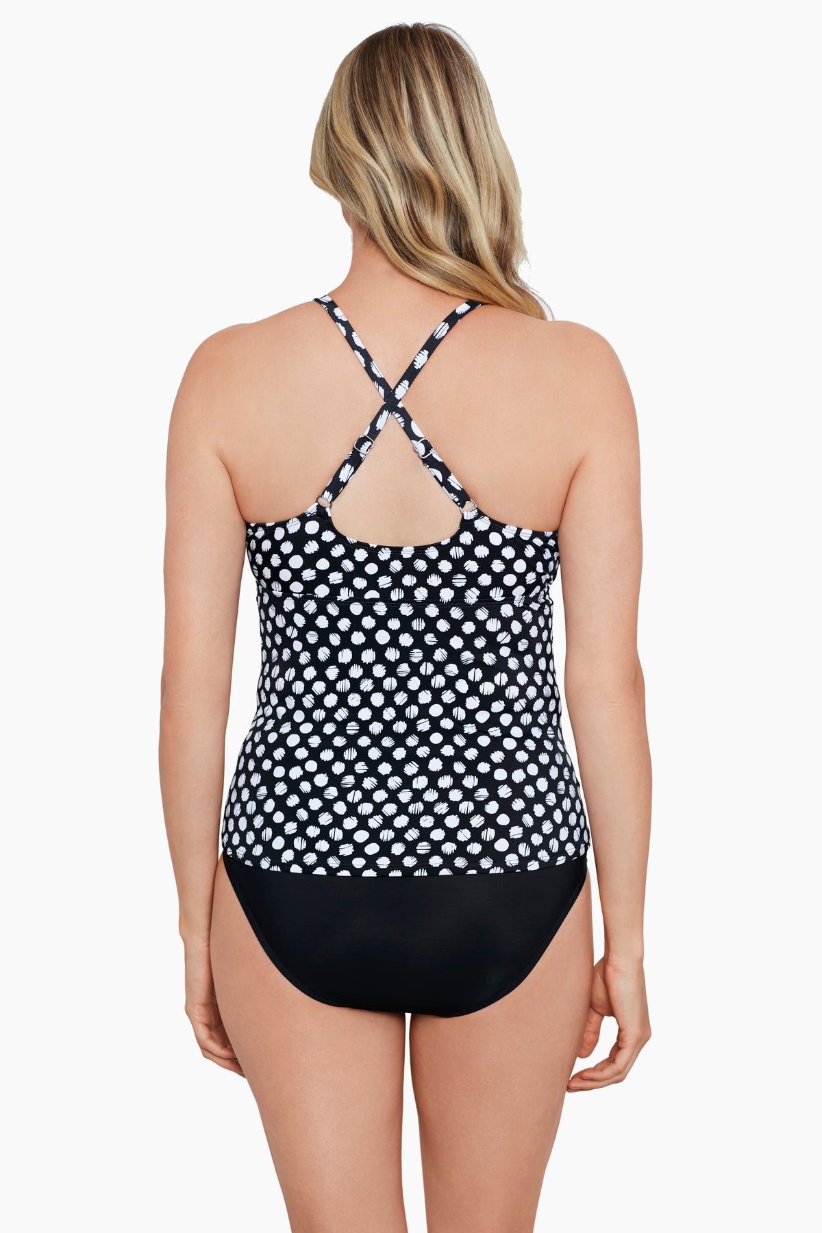 Woman turned away wearing a black and white polka dot peep hole tankini top