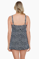 Woman turned away wearing a black and white polka dot tiered ruffle swim dress