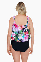 Woman turned away wearing a tropical printed blouson one-piece swimsuit