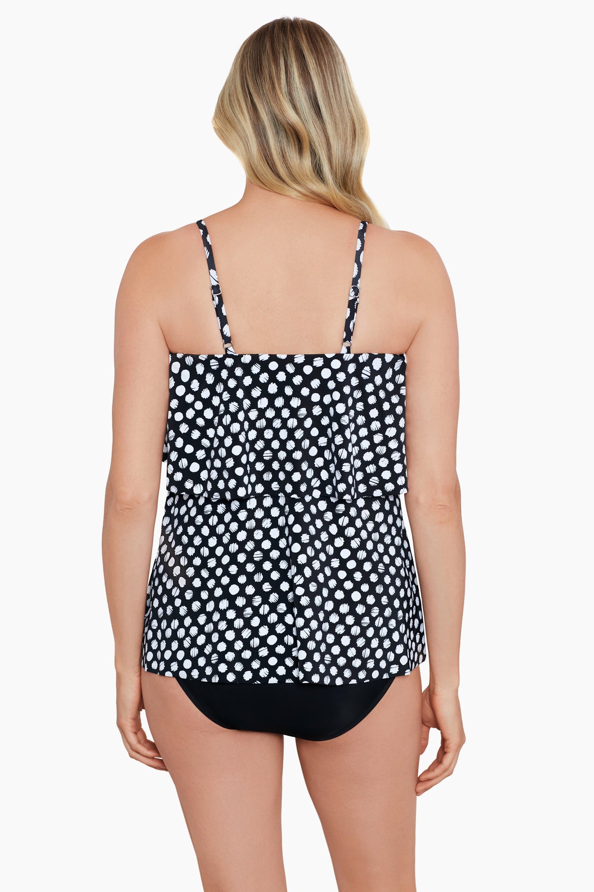 Woman turned away wearing a black and white polka dot ruffled tankini top