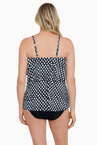 Woman turned away wearing a black and white polka dot ruffled tankini top
