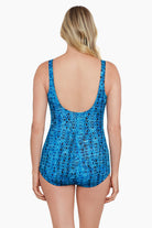 Woman faced away wearing a blue diamond pattern shirred front one-piece swimsuit