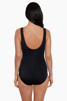Woman faced away wearing a black and blue tie-dye-esque printed one-piece swimsuit