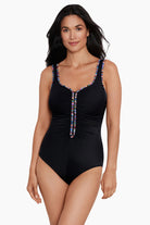 Woman wearing a black one-piece swimsuit with rainbow piping on the edges