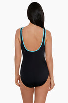 Woman faced away wearing a black one-piece swimsuit with light blue piping on the straps