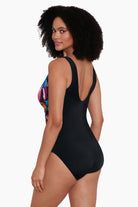 Woman turned left wearing a rainbow paint brush pattern one-piece swimsuit