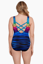 Woman faced away wearing a rainbow ombre with a geometric overlay print one-piece swimsuit