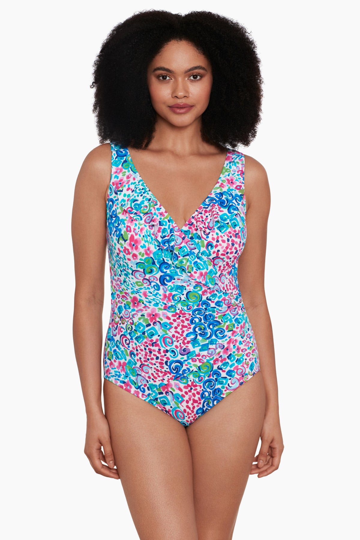 Woman wearing a multicolored swirl and dot printed one-piece swimsuit with a ruffle front