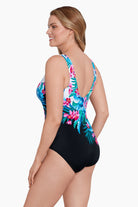 Woman turned left wearing a multicolored floral printed half black and white split one-piece swimsuit