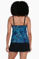 Woman faced away wearing a black and blue petal pattern ruffle faux skirtini one-piece swimsuit