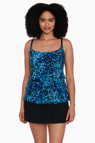 Woman wearing a black and blue petal pattern ruffle faux skirtini one-piece swimsuit