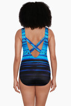 Woman faced away wearing a black and blue ombre abstract print overlay one-piece swimsuit