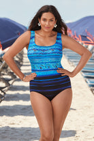 Woman on beach wearing a black and blue ombre abstract print overlay one-piece swimsuit