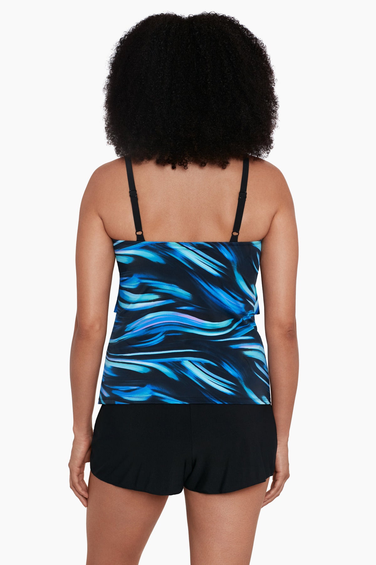 Woman turned away wearing a black and blue oil slick print ruffle tiered one-piece swimsuit shortini